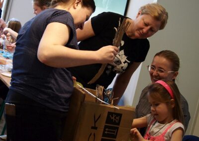 Agata Kurzak pomagająca dzieciom w ułożeniu elementów scenografii w kartonowym pudełku.